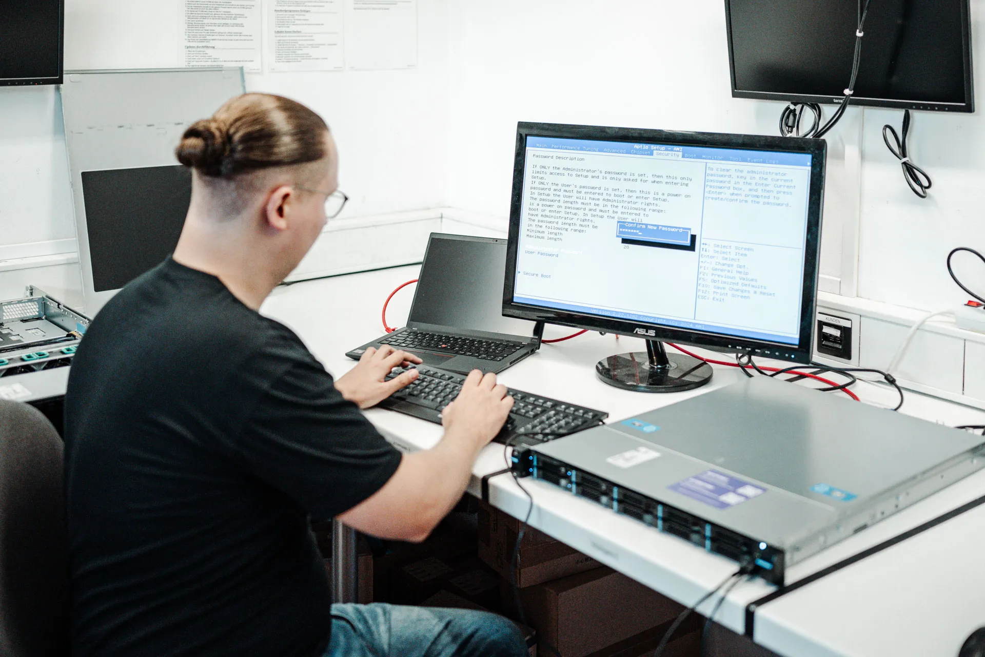 Mitarbeiter arbeitet am Notebook vor einem rot beleuchteten Server-Rack